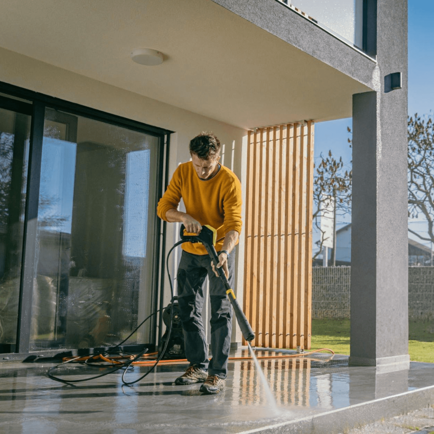 Person cleaning a patio with a pressure washer